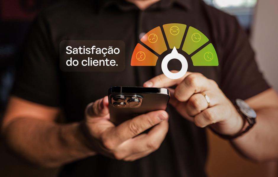 Mãos segurando um celular sob uma caixa com o texto 